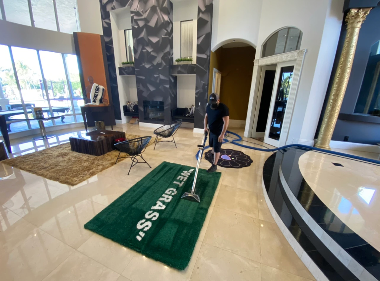 Technician steam cleaning a large area rug in a lobby