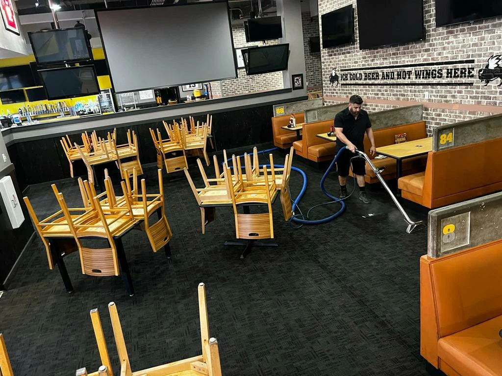 Steam cleaning a restaurant floor with chairs stacked aside