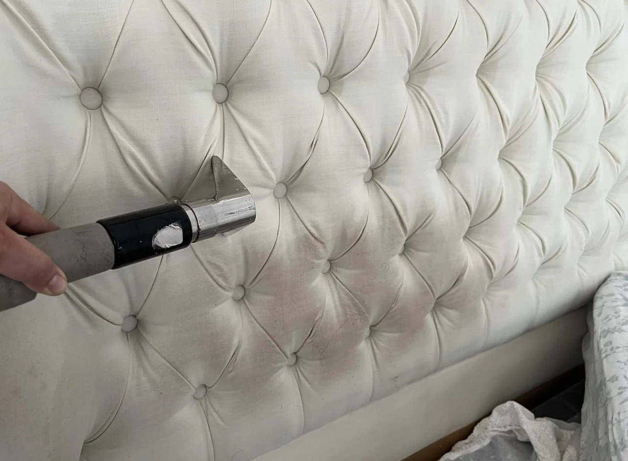 Cleaning a soiled tufted headboard with an extraction tool